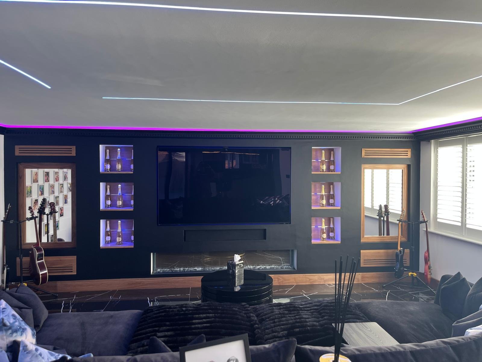 Recessed LED-lit display niches either side of a built-in TV and fire